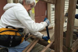 Woman working on porch with crow bar